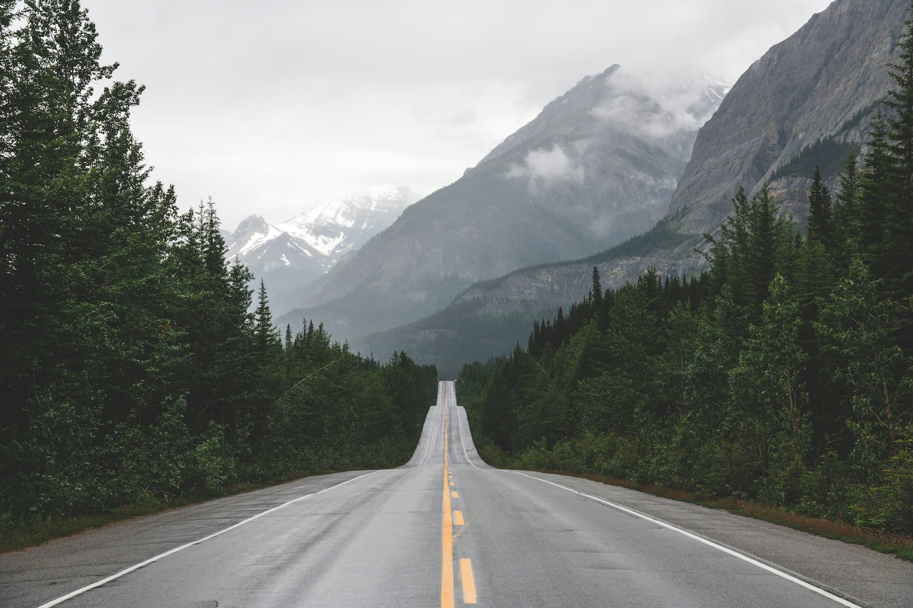 An empty road leading into snowy mountains
